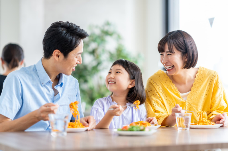 抜歯を伴うマウスピース矯正をして快適になった歯で家族と食事をするイメージ